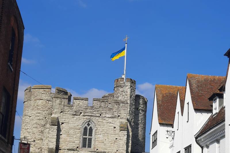 Two women in floral dresses tie notes to a fence