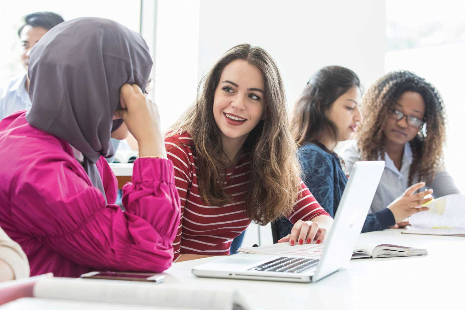 Students working on a laptop and talking