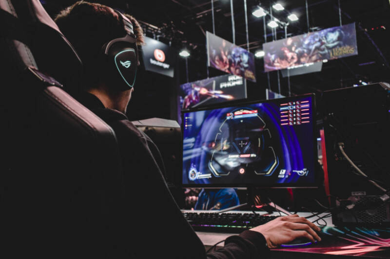 Student wearing headphones and working on a number of computer screens